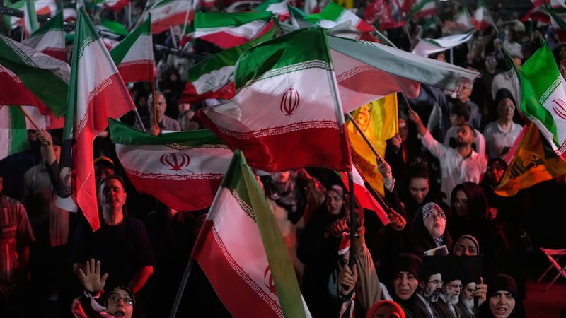 Pro-government demonstrators wave Iranian flags in a gathering at a square in Tehran, Iran,...